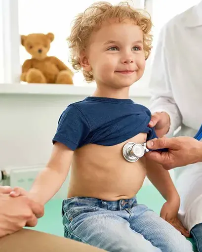 Niño en el doctor sonriente con estetoscopio en el pecho