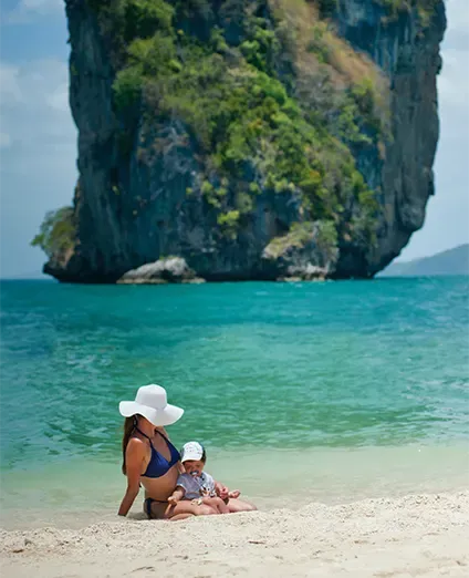 Playa, mujer sentada en la arena con su bebe